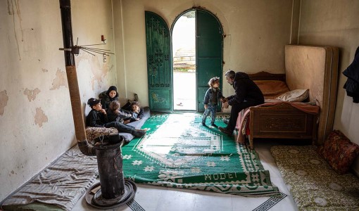 Ahmad och hans fru Salima sitter tillsammans med sina bar i rummet där de bor utanför Aleppo i Syrien. Familjer har varit på flykt sedan 2012.
