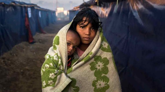 Morsheda (12 år) och Nisma (10 månader) går en promenad tidigt på morgonen i Kutupalong-lägret i Bangladesh för att värma upp sig från kylan i sin bostad. 