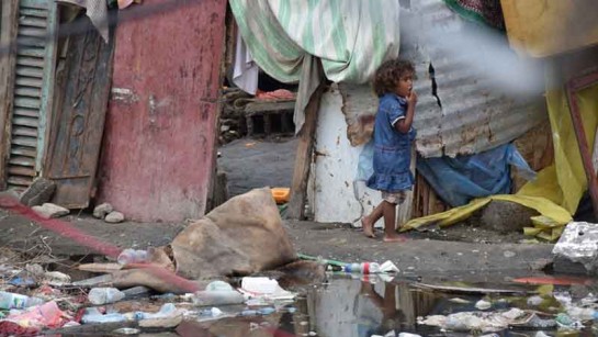 Ett barn vandrar runt i ett översvämmat läger i Aden, Jemens huvudstad. March 2020.