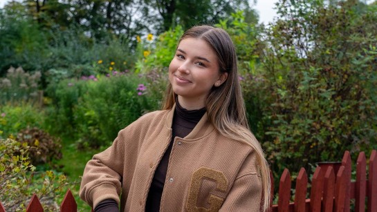 Maria Sur står bland i en park med blommor och buskar.