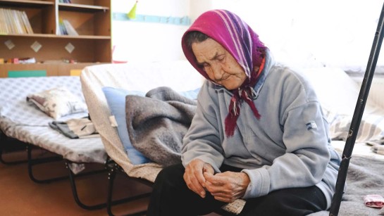 En kvinna på flykt i Ukraina ser nedstämd ut i en sovsal.