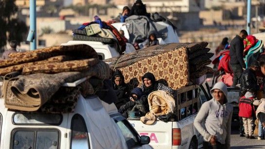 Människor sitter på flakbilar och återvänder till Syrien.