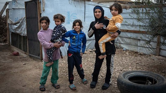 En familj på flykt från Syrien står utanför sitt skjul i Libanon.