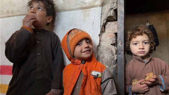 Tre barn står utanför sitt hem i Afghanistan.