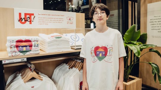 En kille står i en t-shirt med ett motiv han har skapat med temat Vad betyder ett hem för dig?