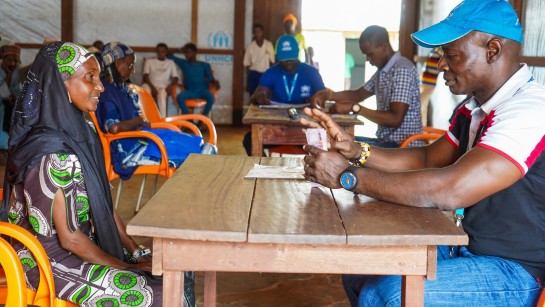 Halimatou får kontantstöd av en UNHCR-medarbetare som räknar sedlar att räcka över.