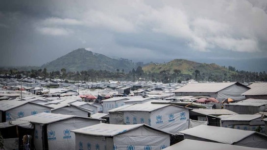 Bild på ett läger för internflyktingar i östra DR Kongo, där hus med UNHCR:s blå logotyp syns.