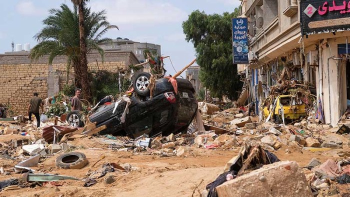 En man står vid brevid en förstörd bild efter en kraftfulla storm och enorma regnmängder slagit mot Libyen. 